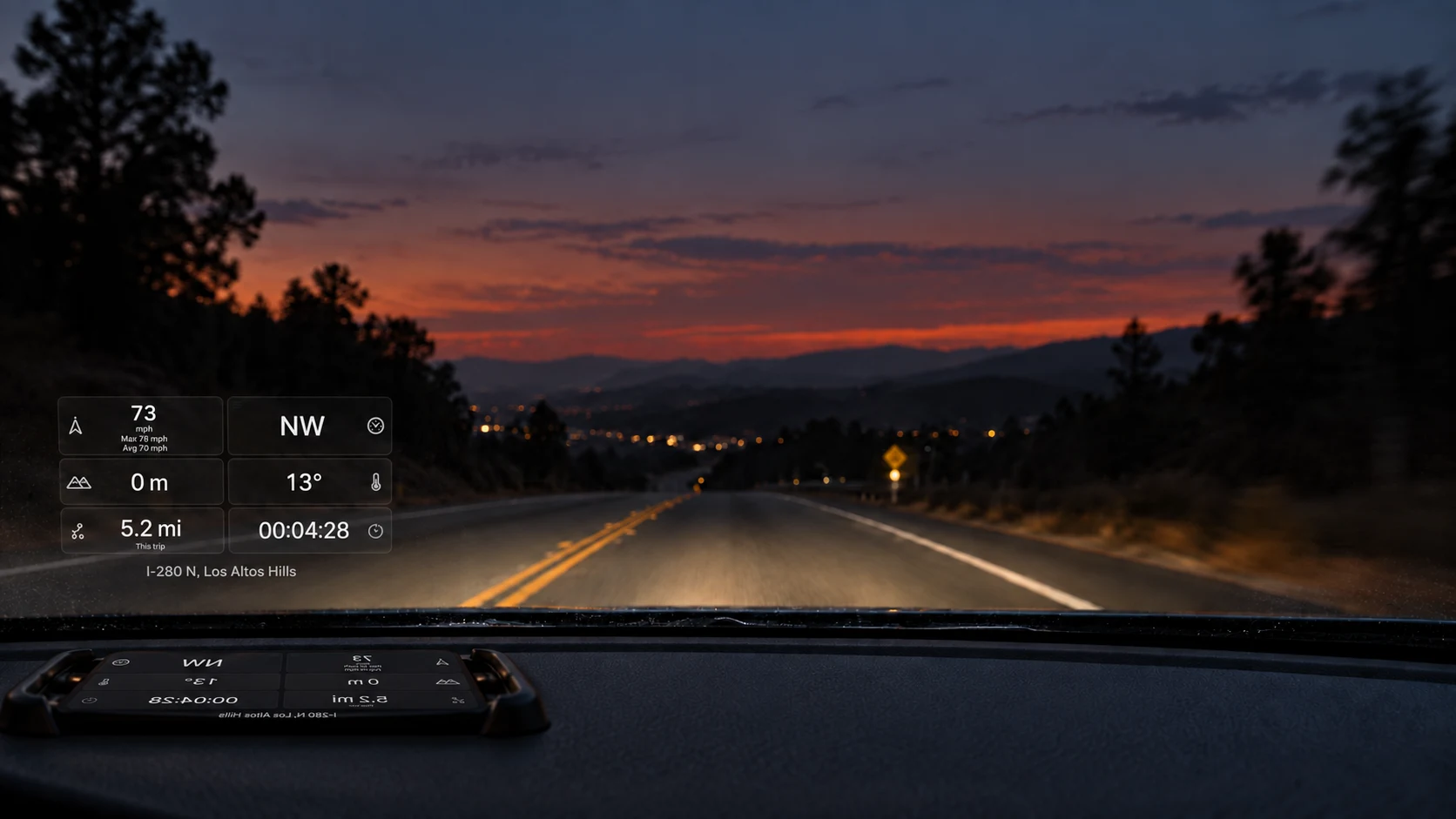 DriveWing windshield HUD illustration showing driving metrics reflected above an iPhone at dusk
